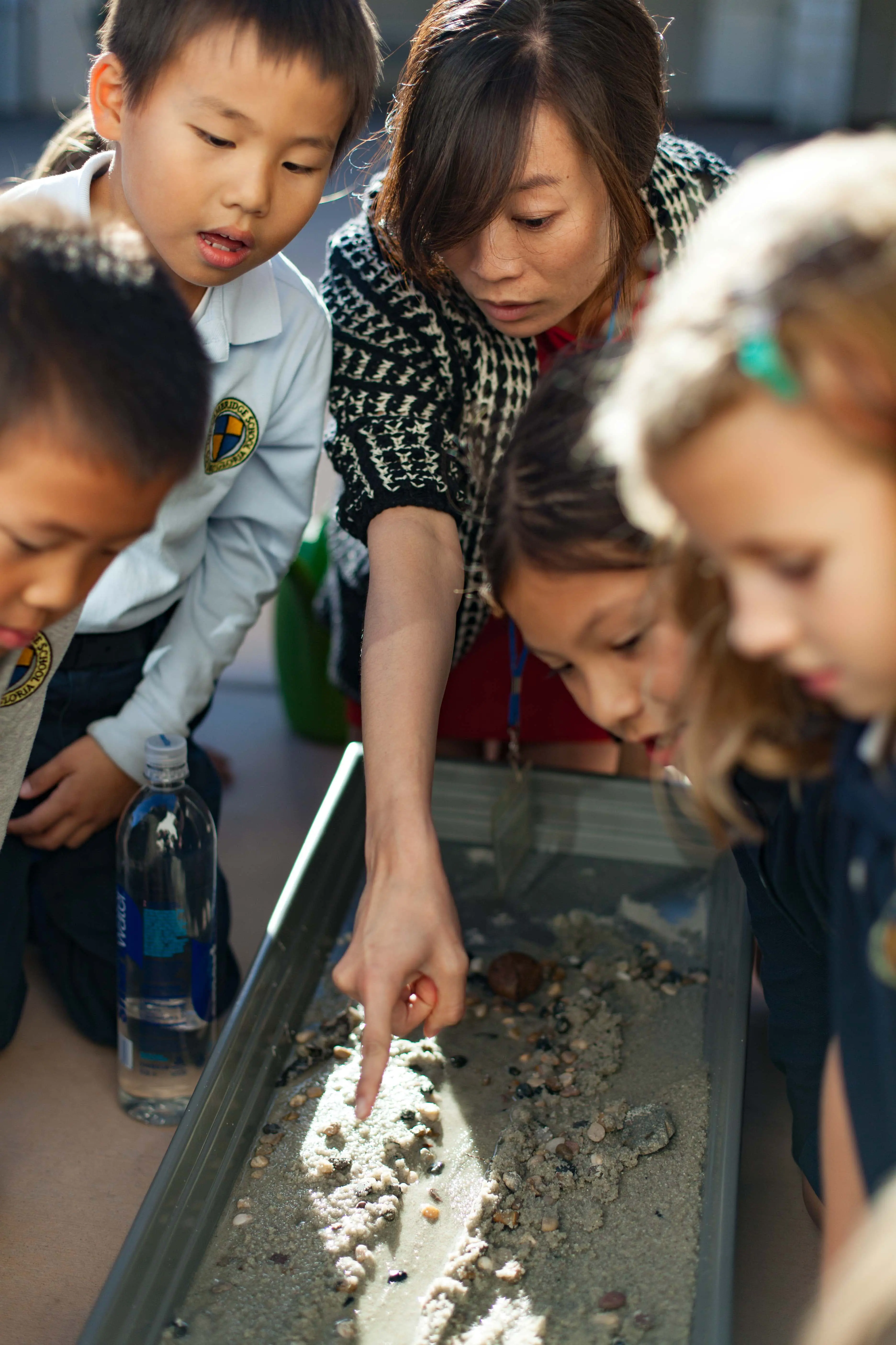 students gather around a science experiment led by a masterful teacher.
