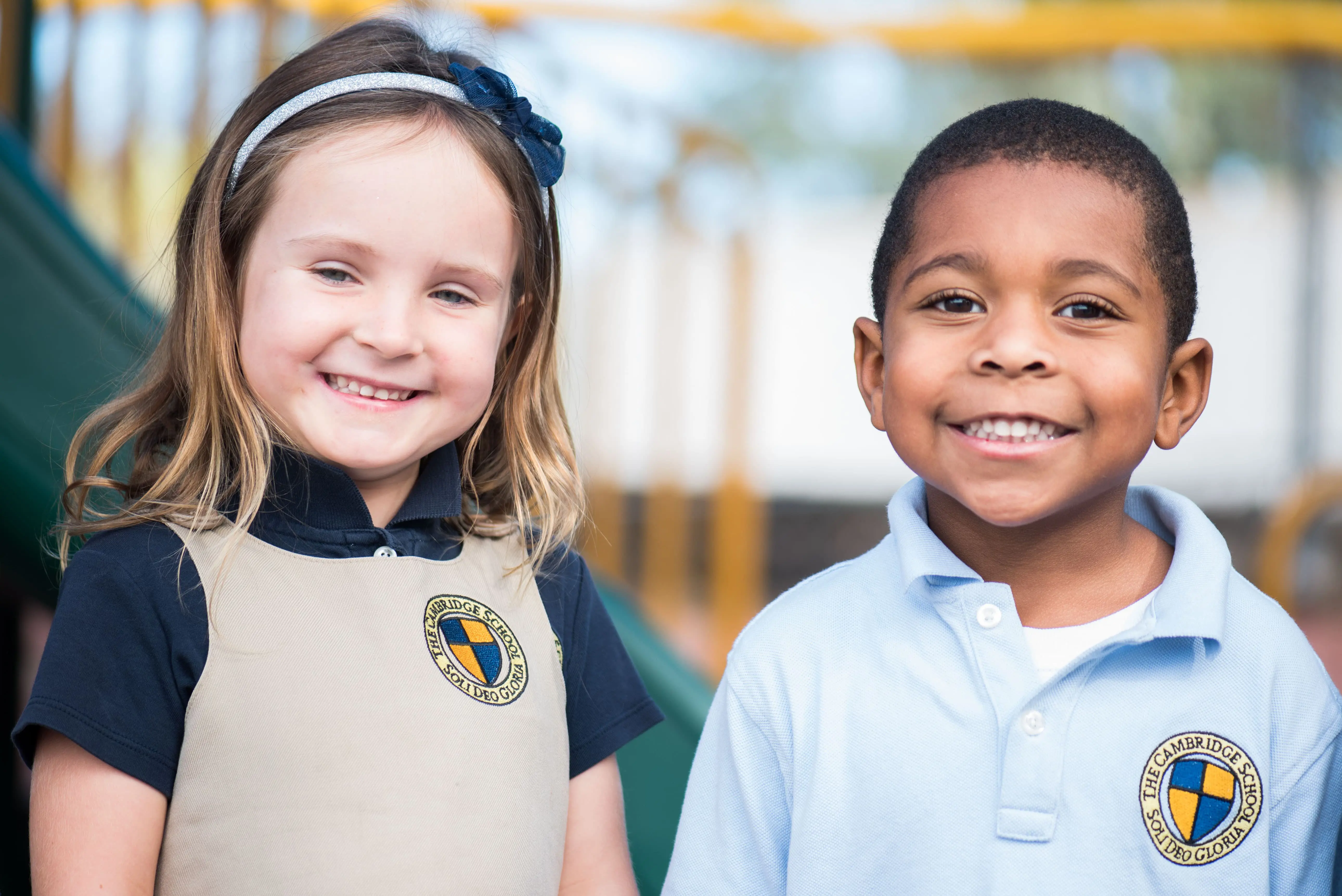 Two Kindergarten Prep students on the playground enjoying structured play and smiling for the camera.
