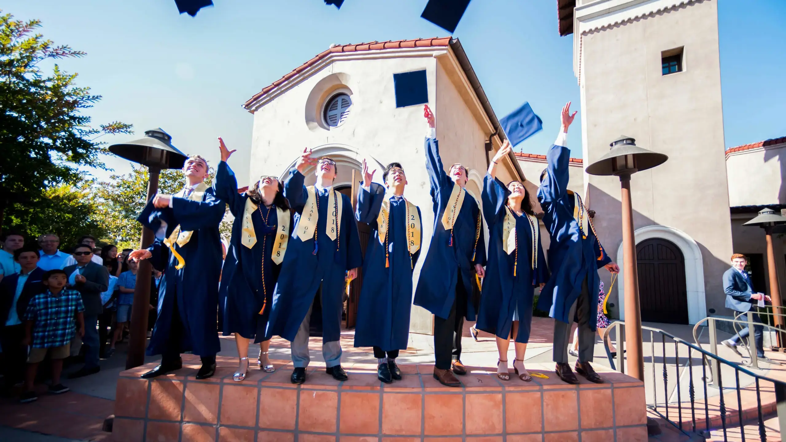 Members of The Cambridge School's first graduating class in 2018 joyfully toss their caps in the air, celebrating a classical Christian education rooted in truth, goodness, and beauty.