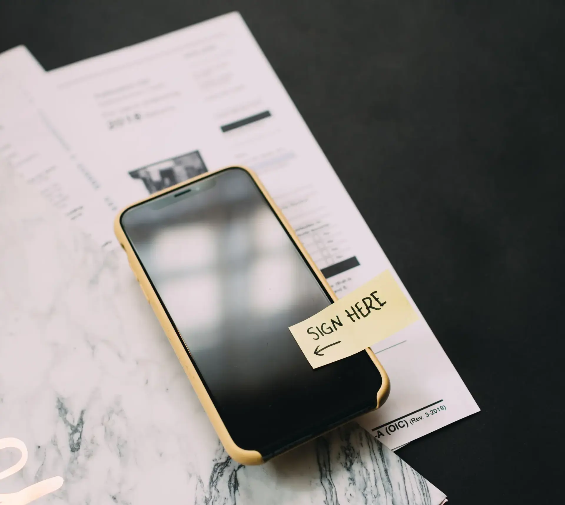 Mobile phone with post-it attached saying 'sign here'