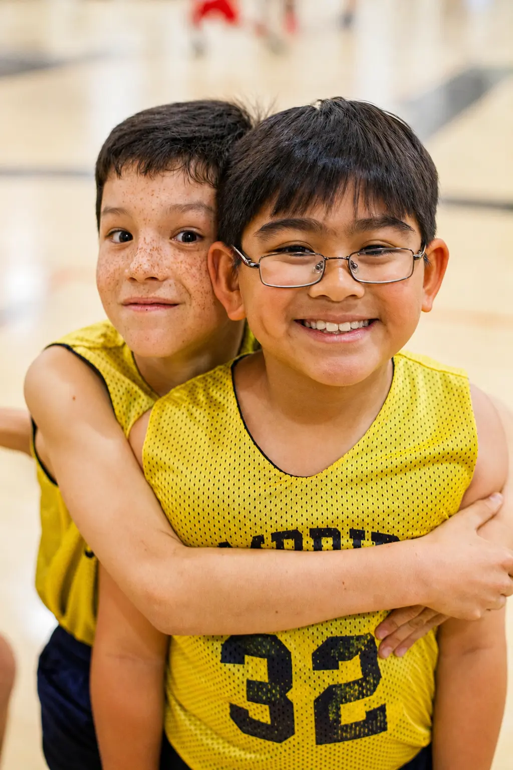 Two middle school students at The Cambridge School, the number one Christian k12 school in California, embrace on a basketball court.
