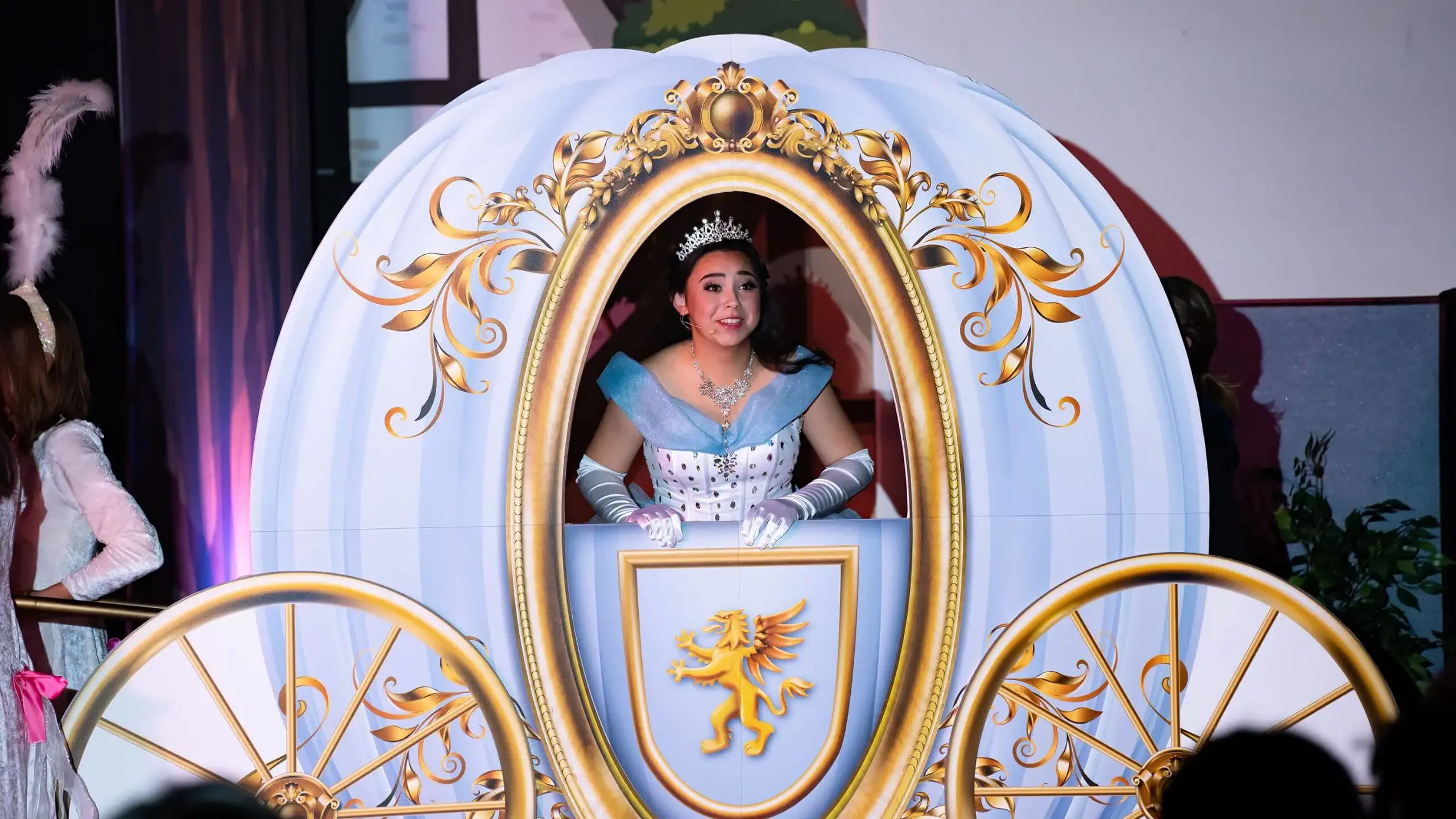 A Cambridge School student performs as Cinderella, dressed in a ballgown and tiara inside a decorative carriage, during the school's musical production.