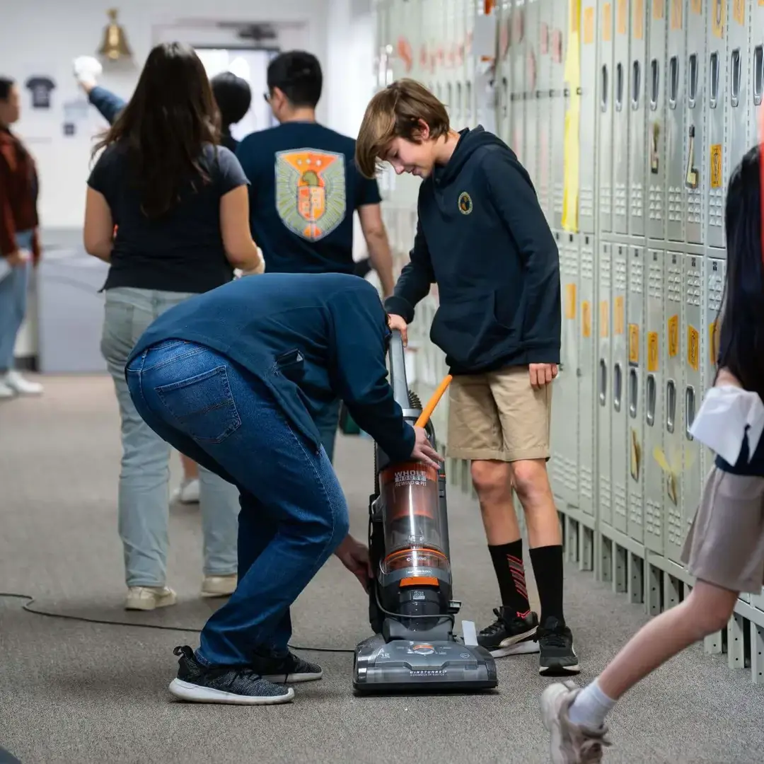 Cambridge upper school students joyfully serve their community by cleaning the upper-school hallway together during Ministerium.