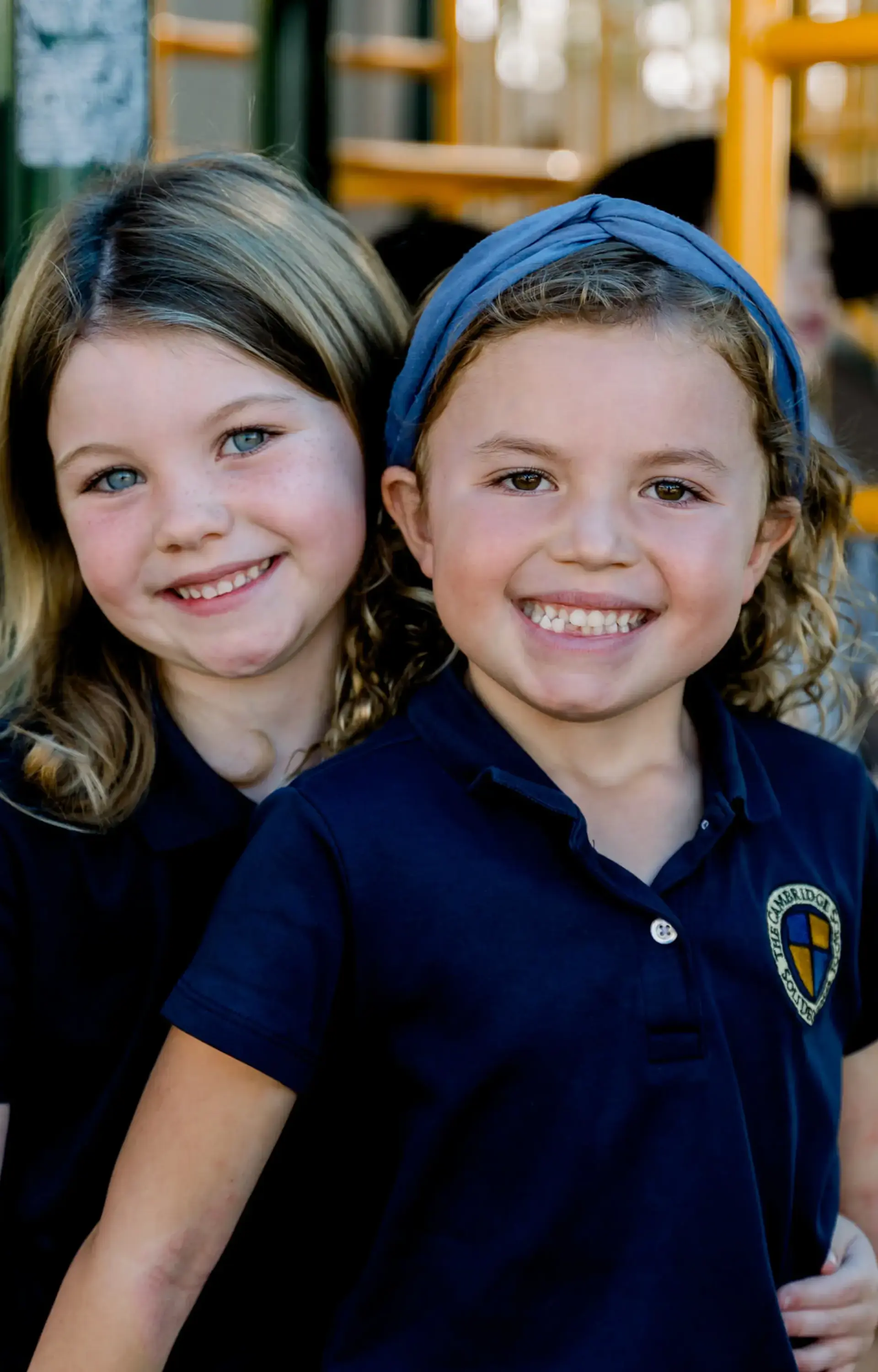 Two students smiling in front of playground equipment