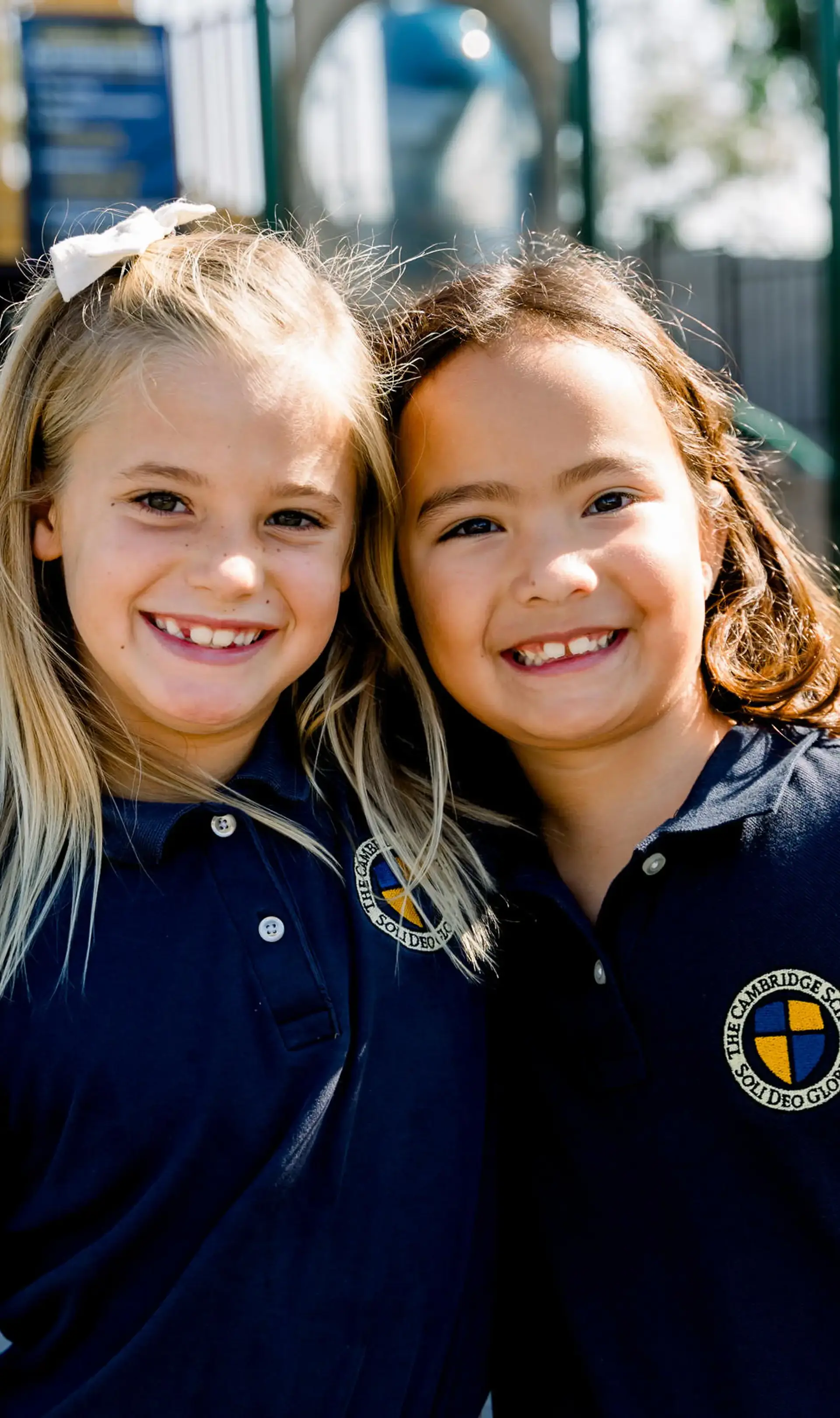 Elementary School students at The Cambridge School smile and embrace on the playground.