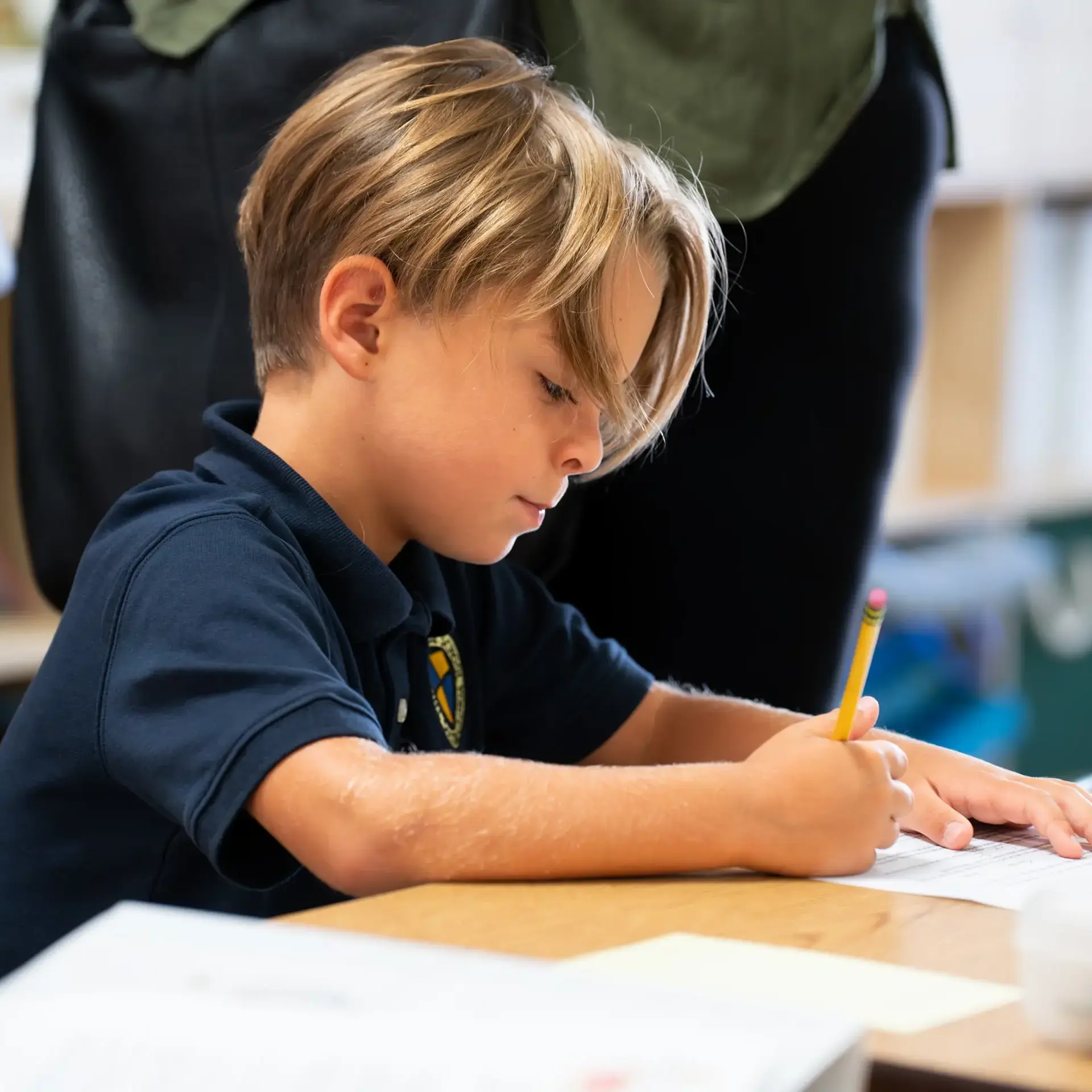 Young student at The Cambridge School focused on writing during class, embodying the intentional and formative education of one of the best private elementary schools in San Diego.