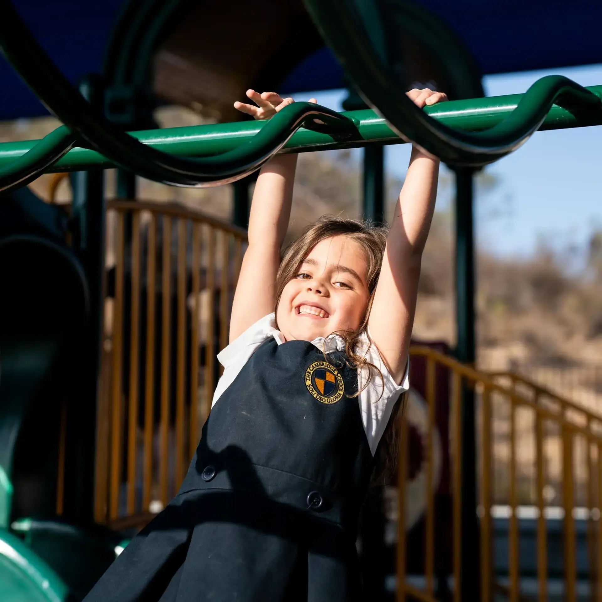 Smiling student at The Cambridge School climbs on the playground during recess at one of the best private elementary schools in San Diego, a classically educated and Christ-centered environment.