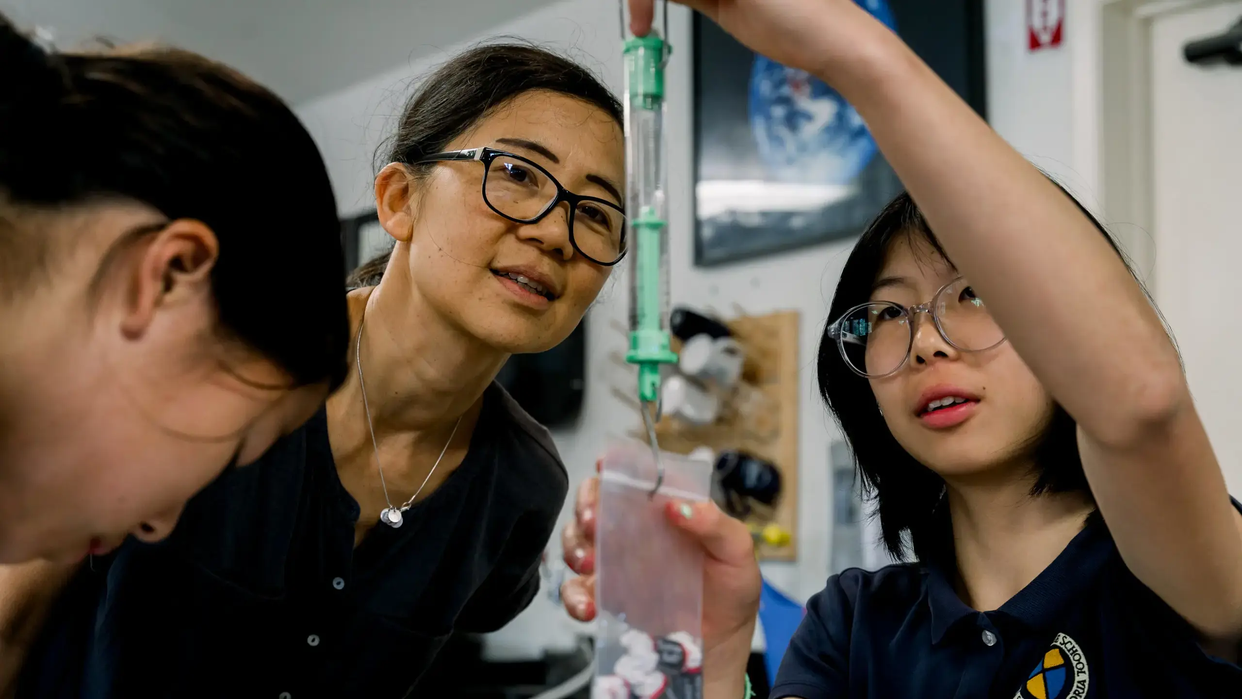 Teacher and two students at The Cambridge School conduct a science experiment in a classroom, demonstrating hands-on learning and academic engagement in a Christian classical education setting.