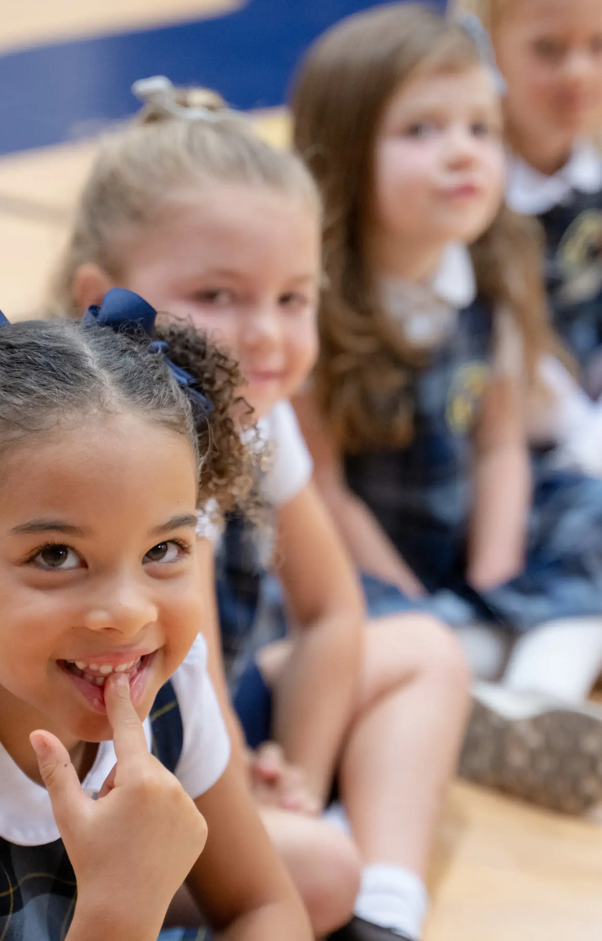 Young students at The Cambridge School dressed in uniforms sit in a line, smiling and preparing for picture day at one of the best private elementary schools in San Diego.