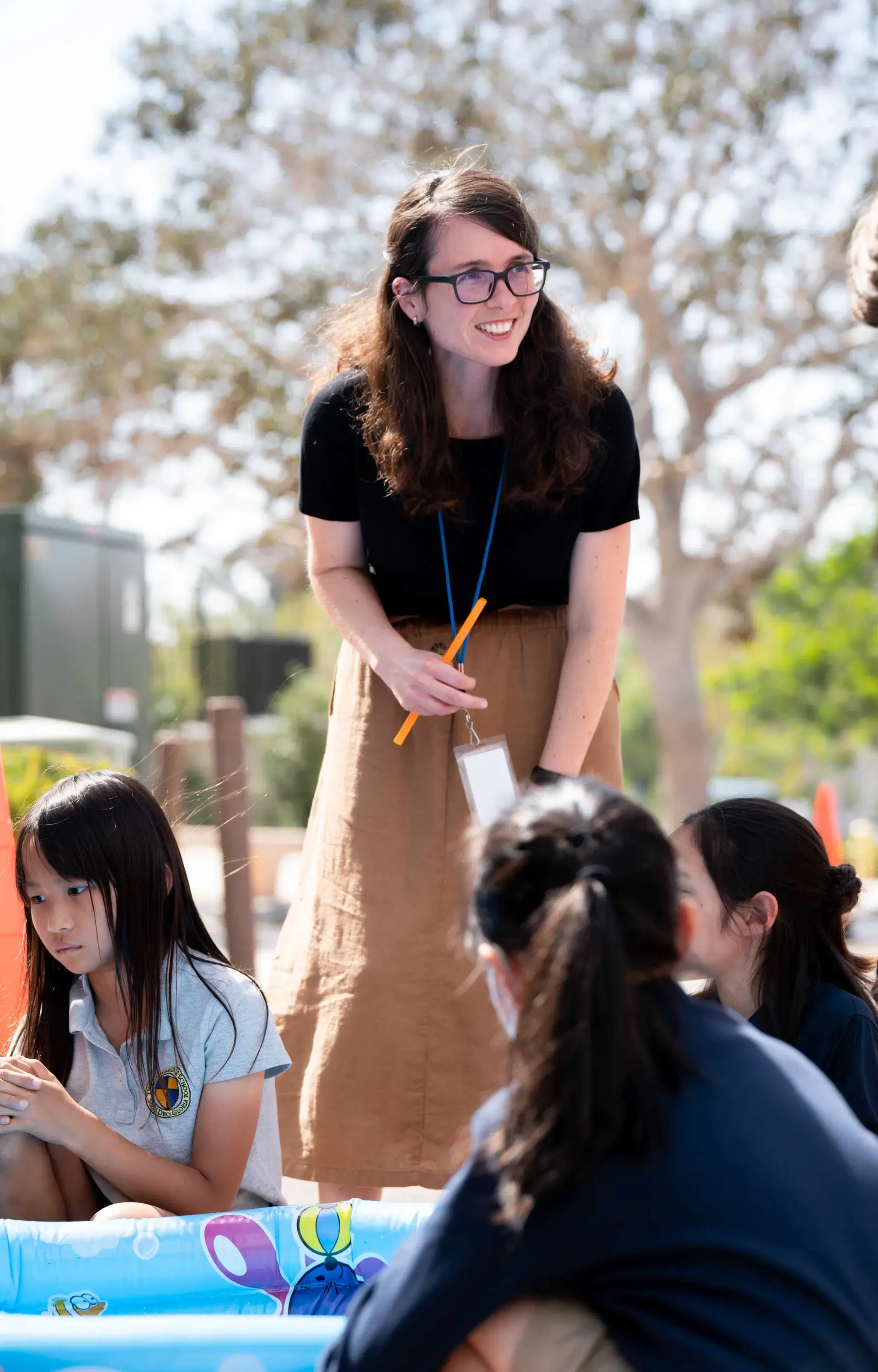 Kindergarten teacher leaning over group of children on playground