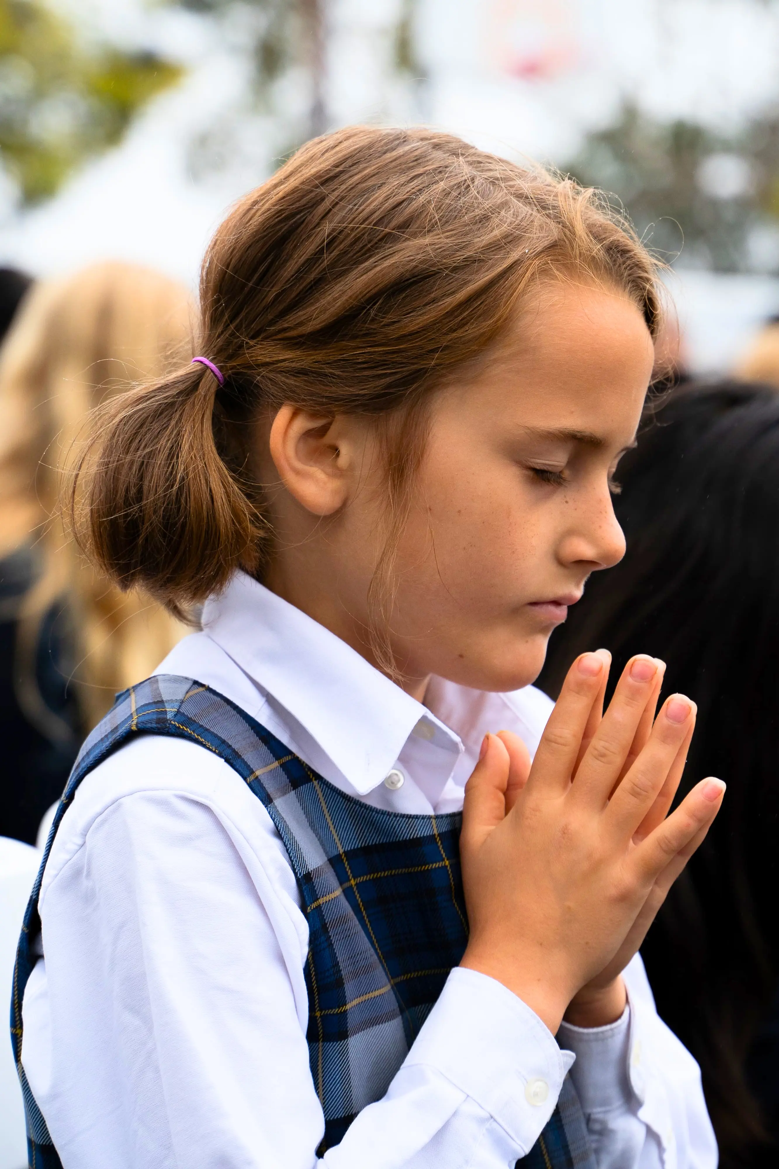 Young female at The Cambridge School in deep prayer at a school event.