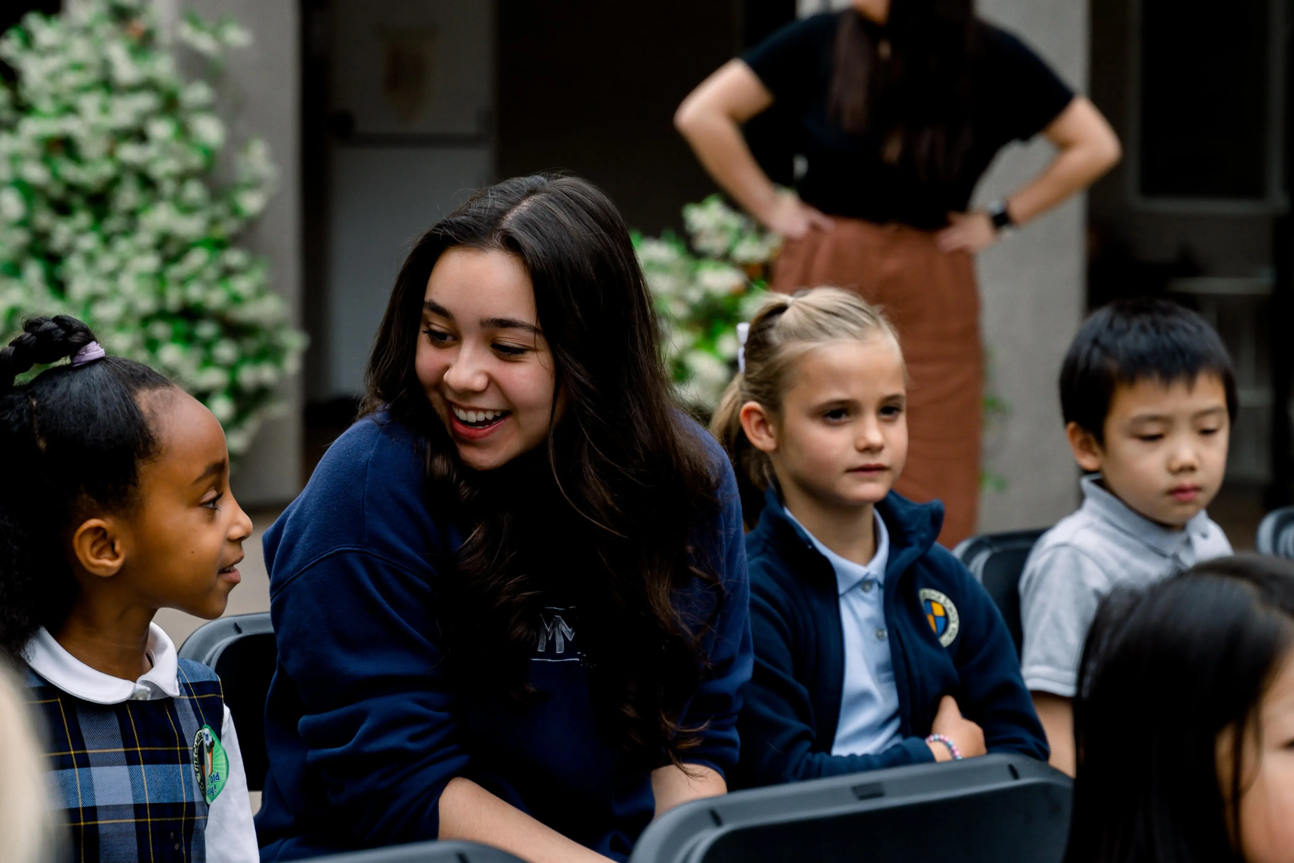 Senior student and Kindergarten student converse at a school event.