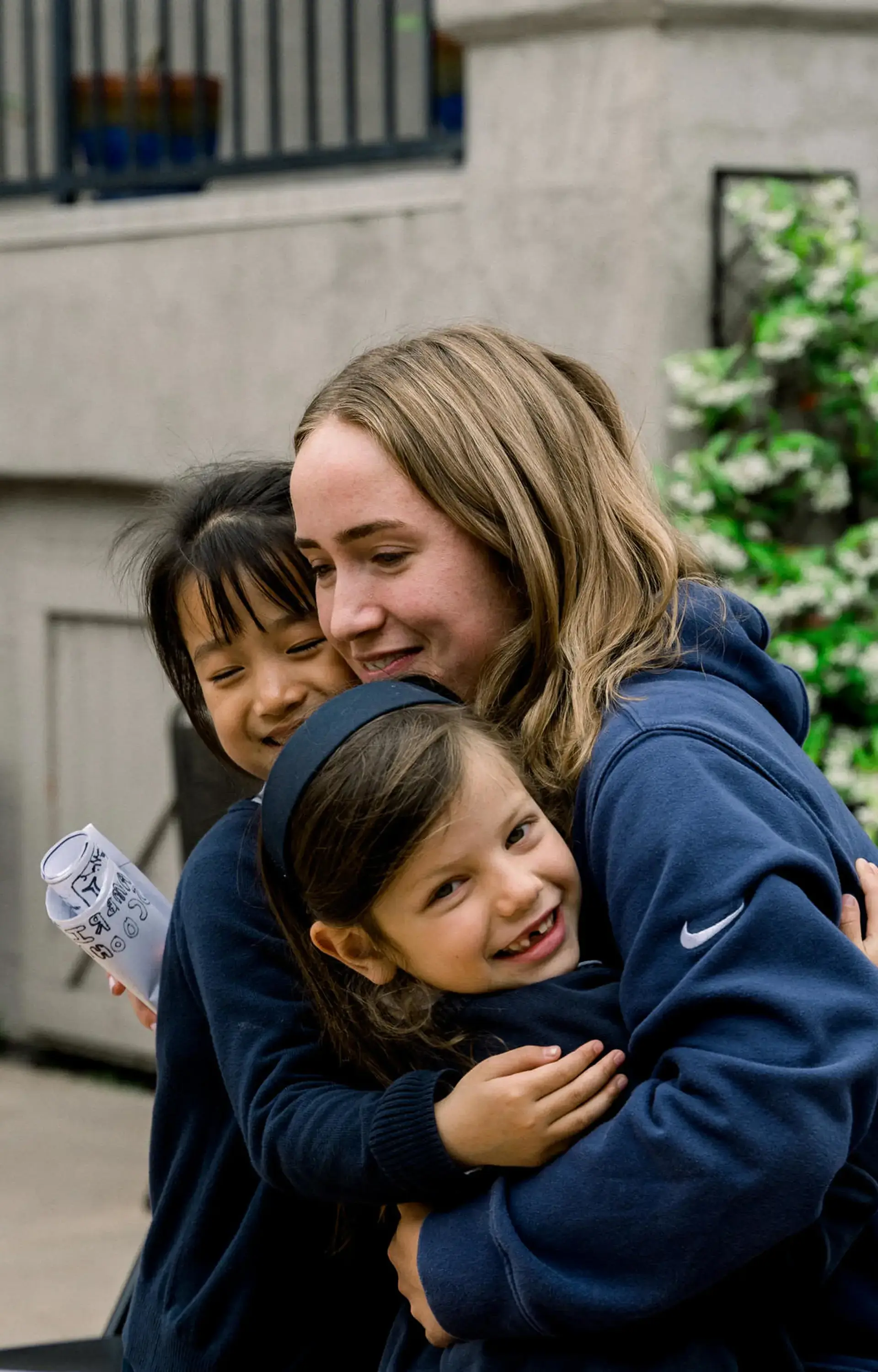 A senior student at The Cambridge School hugs two kindergarteners, illustrating the school’s classical Christian education, mentorship, and close-knit San Diego private school community.