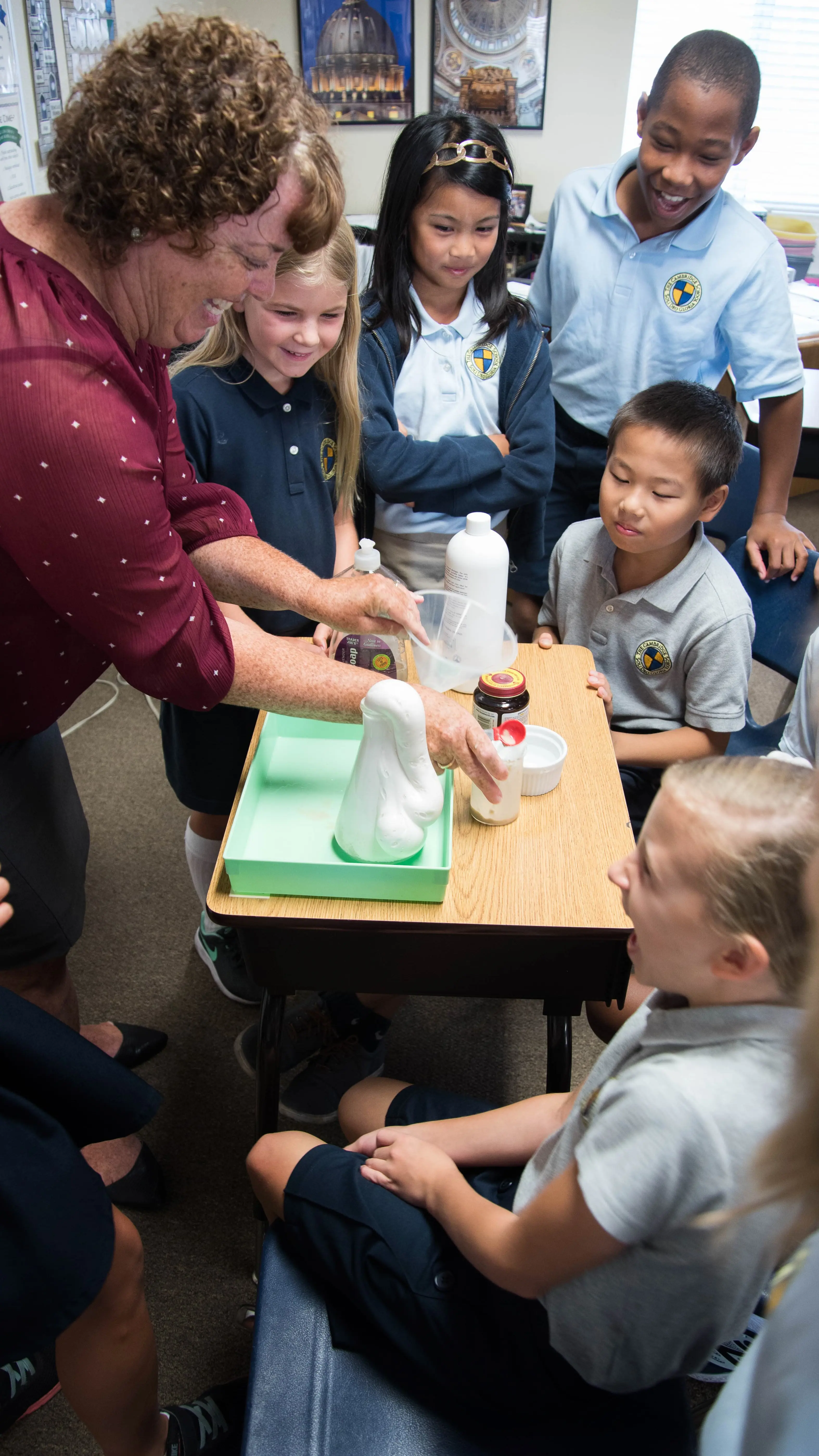 Elementary school students at The Cambridge School, the number one k12 school in San Diego, gather around a science experiment, filled with wonder.