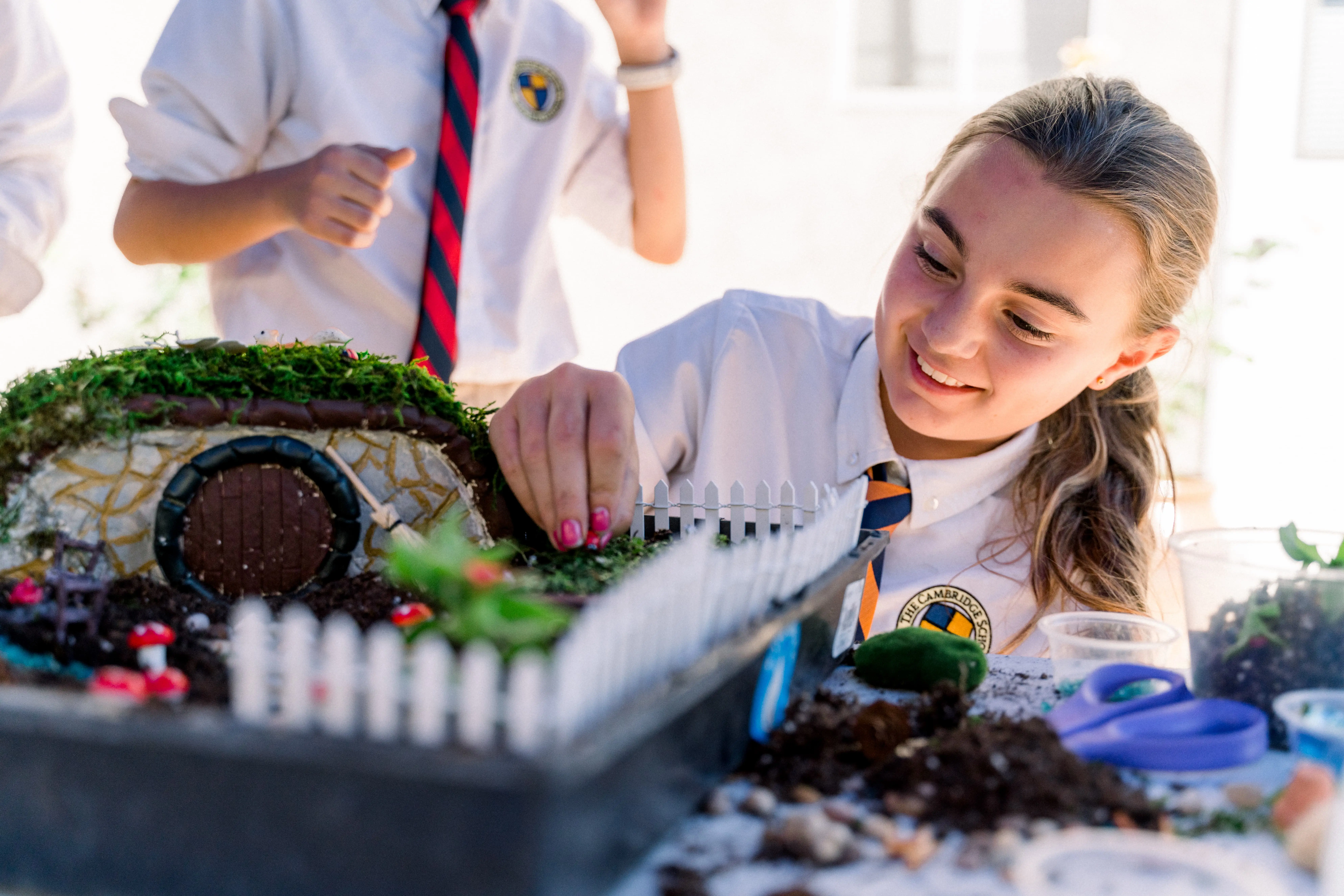 smiling student building a hobbit house out of local San Diego vegetation - an integration of their science and literature programs 